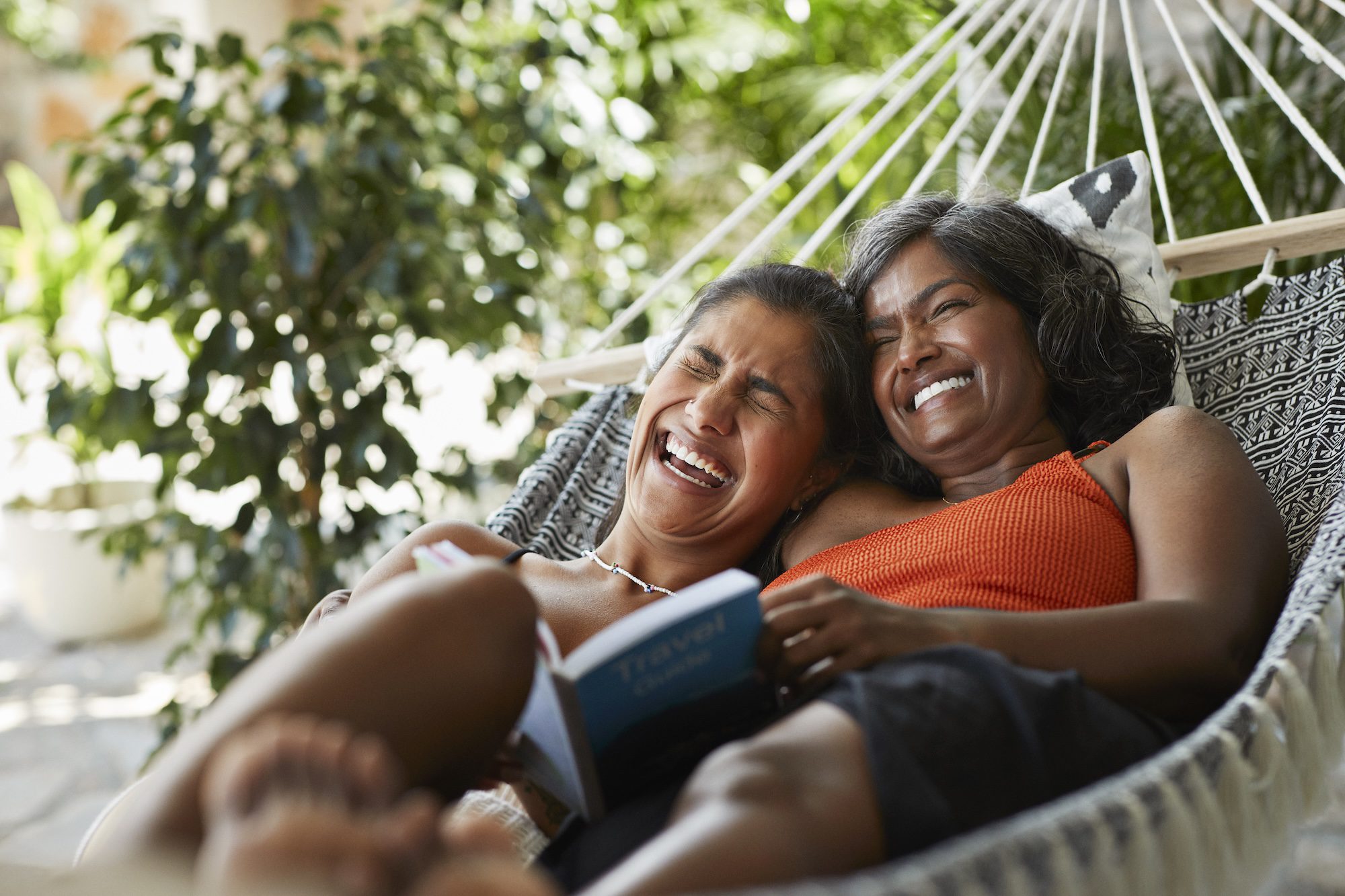 Cheerful woman lying with mother in hammock